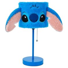 a blue hat with ears and eyes on top of a metal stand in front of a white background