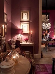 a living room filled with furniture and a chandelier hanging from the ceiling next to a table