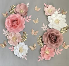 paper flowers and butterflies on a gray background with gold foil leaves, one large pink flower surrounded by smaller white ones