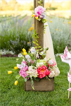 a wooden cross with flowers on it in the grass next to a white chair and an umbrella