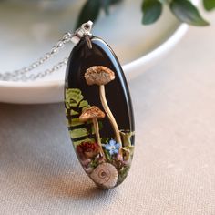 a glass pendant with mushrooms and flowers on it sitting on a table next to a plate