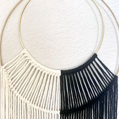 two black and white macrame pieces hanging on a wall with gold hoop holders