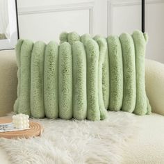 four green pillows sitting on top of a white couch next to a wooden tray with soap