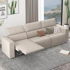 a living room with a sectional couch and pillows on the floor next to a window