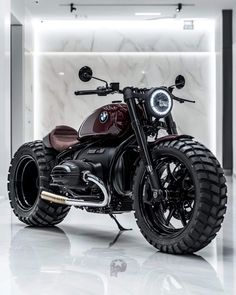 a black motorcycle parked in front of a white wall with lights on it's side