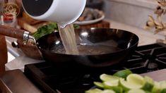 a person pouring water into a frying pan on top of a gas stovetop