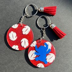 two red and white acrylic key chains with tassels on them sitting on a table