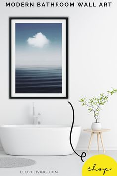 a white bathtub sitting next to a wall with a painting on it and a plant in the corner