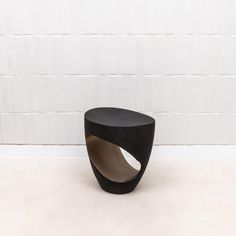 a small black table sitting on top of a white floor next to a tiled wall