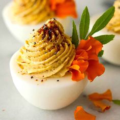 deviled eggs decorated with orange flowers and herbs