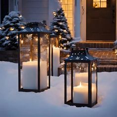 two lanterns with lit candles in the snow