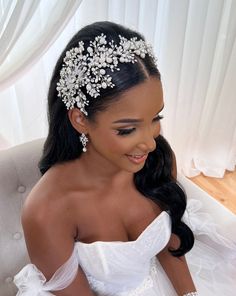 a woman in a wedding dress sitting on a couch wearing a bridal headpiece