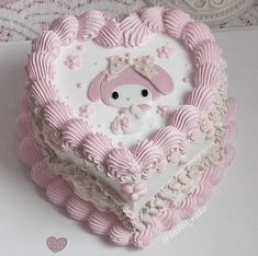 a cake shaped like a heart with a hello kitty face on the top and pink icing