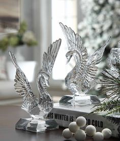 two crystal figurines sitting on top of a book next to a christmas tree