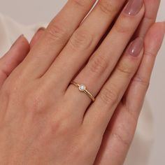 a woman's hand with a diamond ring on top of her left hand,