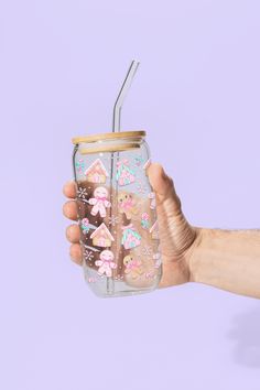 a hand holding a mason jar filled with gingerbreads and pink flowers on it