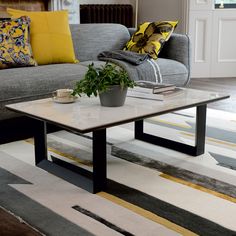 a living room with a couch, coffee table and potted plant on the floor