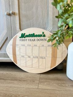 a wooden football shaped calendar sitting next to a potted plant