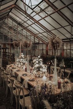 an indoor dining area with tables and chairs covered in tablecloths, flowers and candles