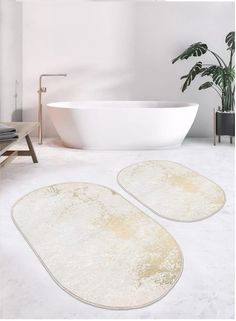 two bath mats sitting on top of a white floor next to a tub and plant