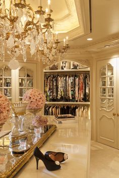 an elegant closet with chandelier and high heeled shoes on the counter in front of it