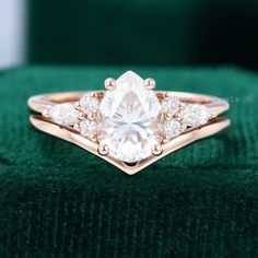 a close up of a ring on top of a green velvet surface with diamonds in the middle