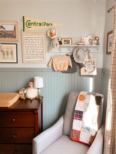 a baby's room with pictures on the wall and a chair in front of it