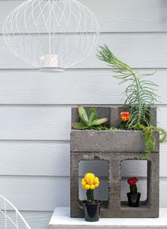 a planter with flowers and plants in it on top of a white table next to a house