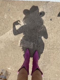 the shadow of a person wearing pink shoes and a hat on their head is seen from above