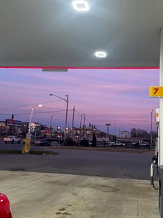 an empty gas station at dusk with cars parked in the lot