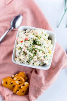 a white bowl filled with coleslaw and pretzels on top of a pink napkin