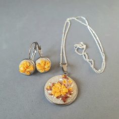 a necklace and earring set with yellow flowers on the front, sitting on a gray surface