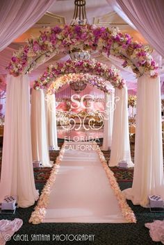 an archway decorated with pink flowers and white draping for a wedding ceremony in california