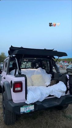 the back end of a white jeep parked on top of a grass covered field