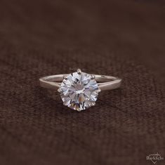 a close up of a diamond ring on a brown cloth with the center stone visible