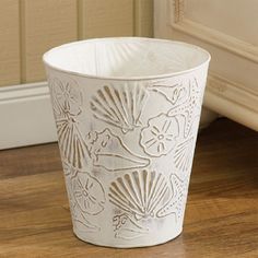 a white cup sitting on top of a wooden table next to a wall and floor