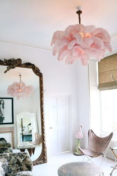 a living room filled with furniture and a large pink chandelier hanging from the ceiling