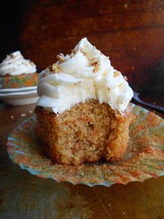 a cupcake with white frosting sitting on top of a green and orange plate