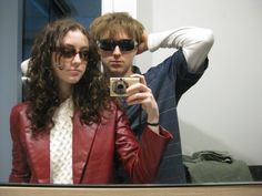 a man and woman taking a selfie in front of a mirror with sunglasses on