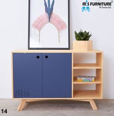 a blue cabinet with two open shelves next to a potted plant and a framed photograph