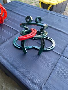 three metal rings sitting on top of a blue tablecloth covered picnic table with yellow and red chairs in the background