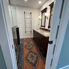 an open door leading to a bathroom with a rug on the floor and sink area