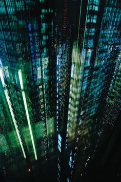 an aerial view of skyscrapers at night with green and blue lights in the foreground