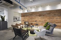 a living room filled with furniture next to a wall covered in wooden planks and plants