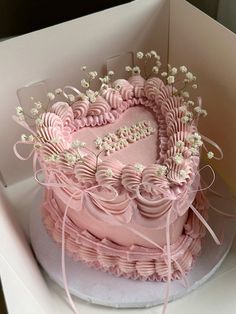 a heart shaped cake in a box with pink icing and white flowers on top