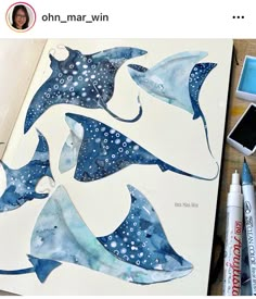 some watercolors are laying on top of a paper with blue and white designs