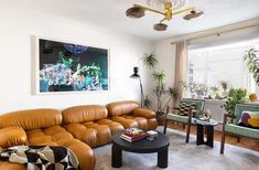 a living room filled with lots of furniture next to a large painting on the wall