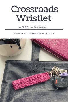 a pink crochet keychain sitting on top of a black leather bag