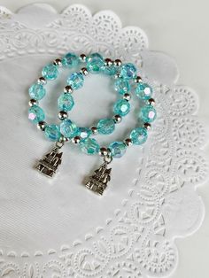 two bracelets with charms are sitting on a doily