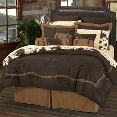 the bed is made with brown and white comforters, along with cow - print pillows